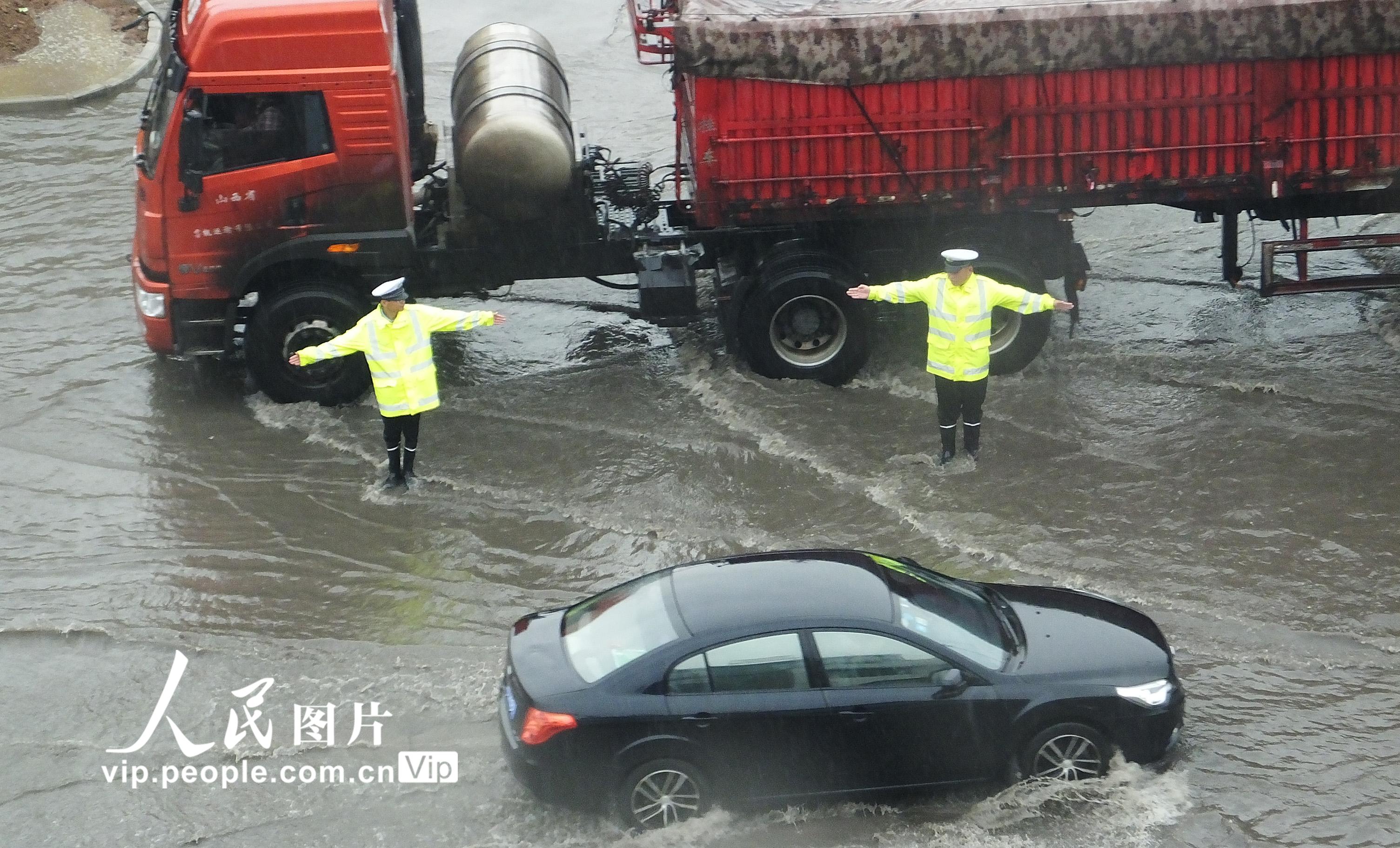 6月16日，山西運城市新絳縣交警大隊汾河灣中隊輔警在108國道汾河灣積水處冒雨指揮交通。 