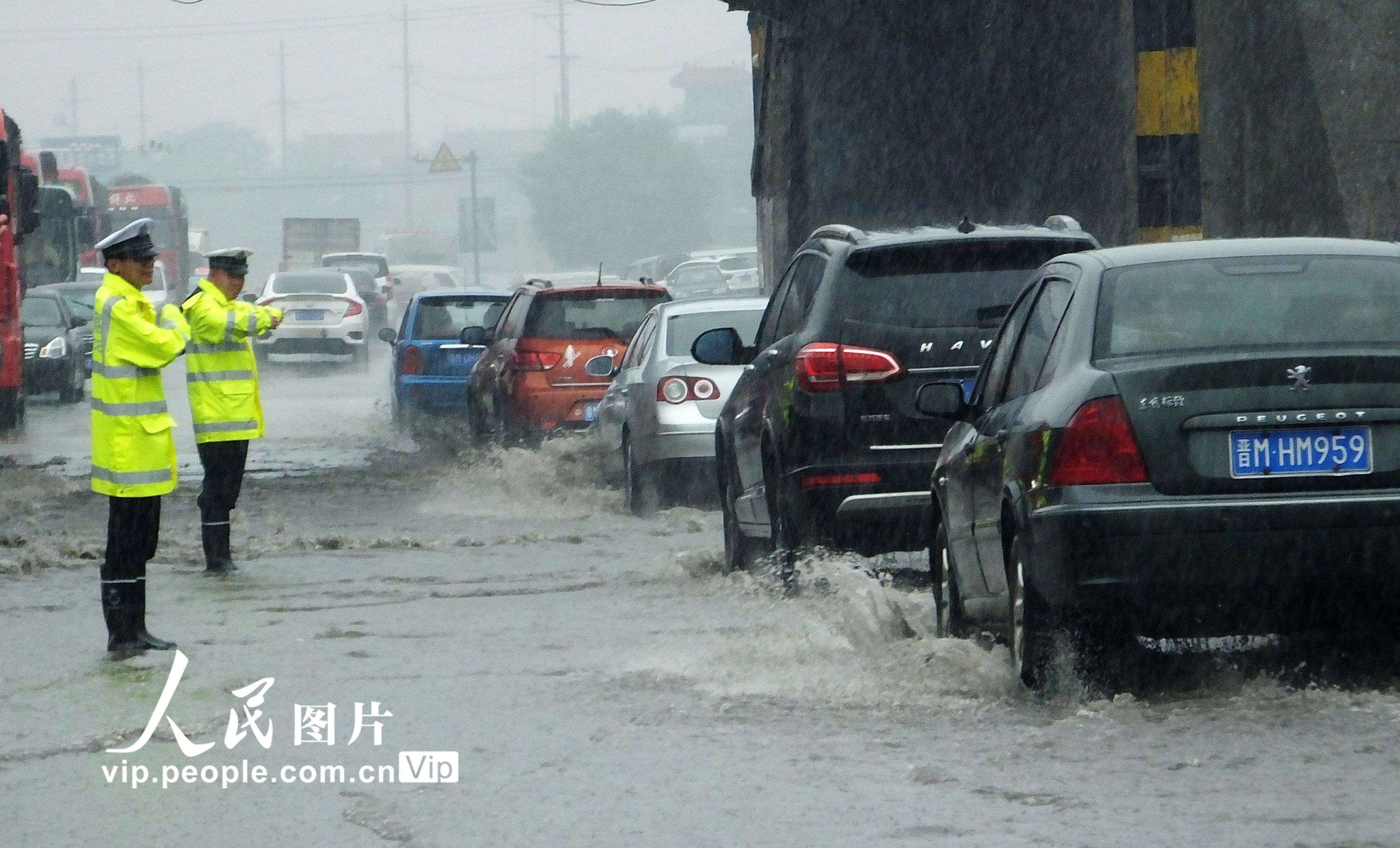6月16日，山西運城市新絳縣交警大隊汾河灣中隊輔警在108國道汾河灣積水處冒雨指揮交通。 