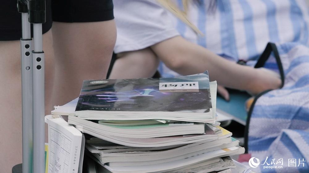 一名中學生正在校門外整理自己的課本。（6月17日）人民網記者 王嘉澍 攝