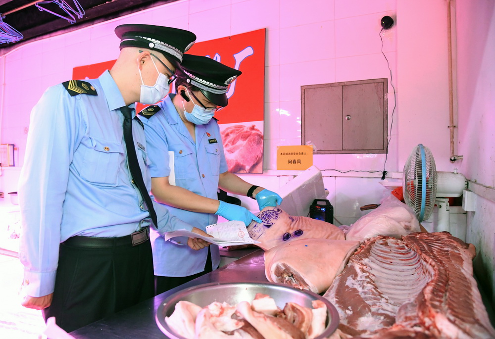 6月17日，在位於北京市海澱區的增光鴻運市場，執法人員對商戶出售的鮮肉進行檢查。