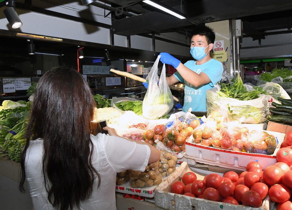 6月17日，在位於北京市海澱區的增光鴻運市場，市民（左）在購買蔬菜。