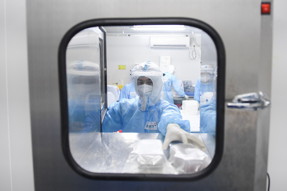 6月26日凌晨，檢驗人員從實驗室傳遞窗內拿取反應試劑 。