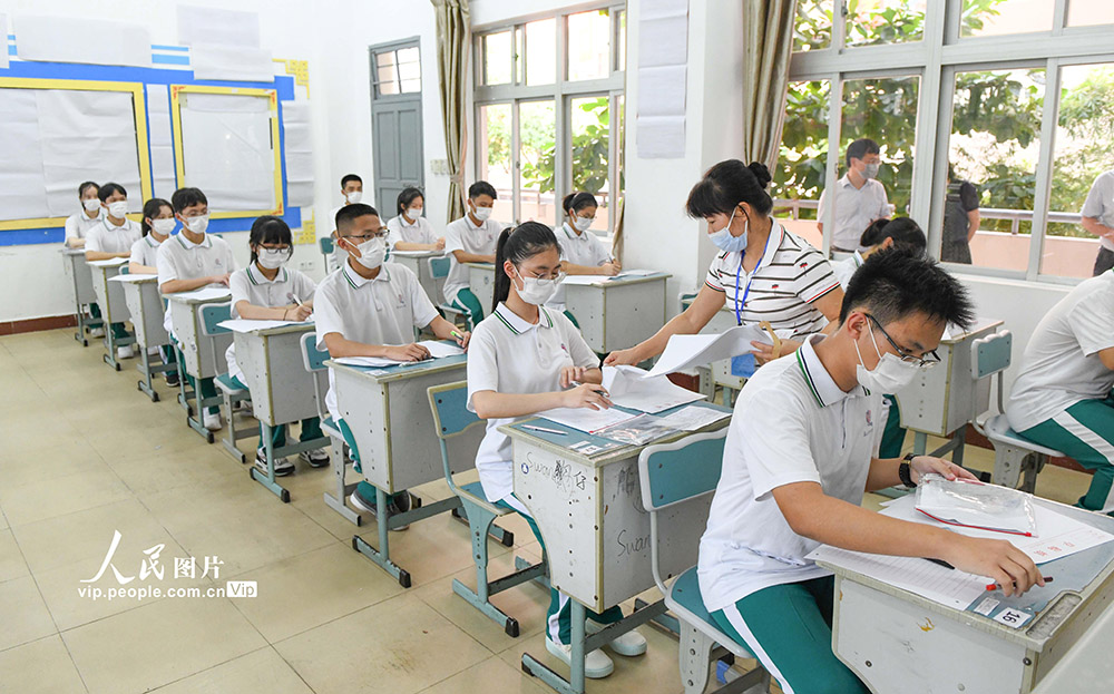 7月2日，海南華僑中學高中部高考模擬演練現場，監考老師為考生發放試卷。