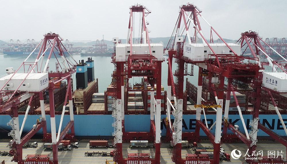 7月9日，一艘外贸集装箱货轮在位于山东自贸区青岛片区的山东港口青岛港前湾集装箱码头装卸货物。（张进刚  摄）