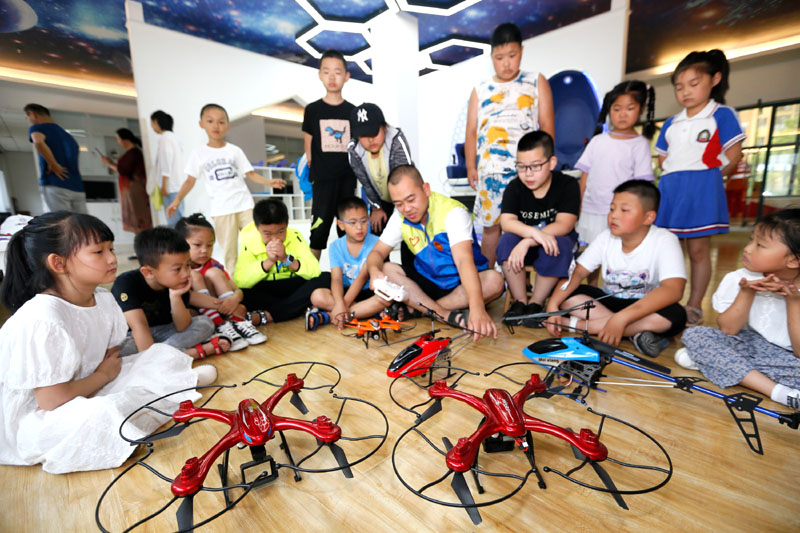 7月12日，山東省青島市即墨區環秀街道濱湖社區科普館工作人員在給小學生講解無人機飛行常識。