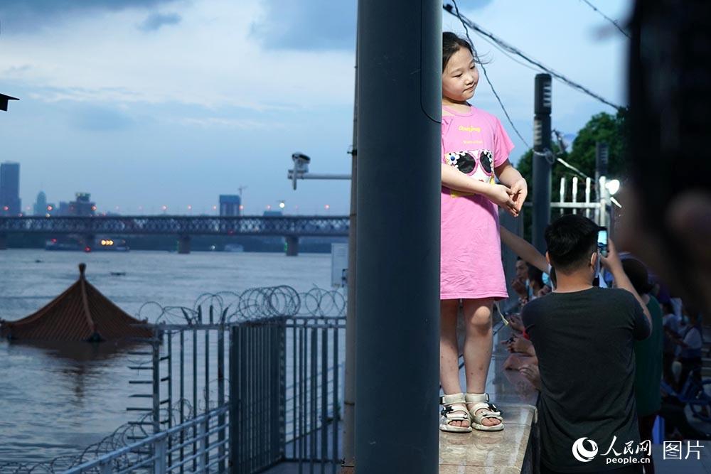 2020年7月13日19时35分，一个小女孩在武昌黄花矶凉亭旁做爱心手势让家长拍照。 