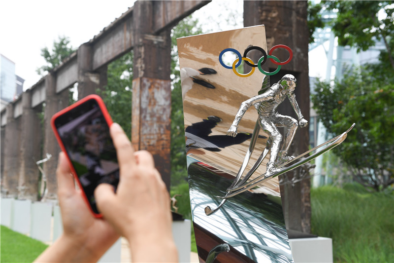 7月13日，參觀者在拍攝展出的雕塑作品《自由式滑雪——翱》。
