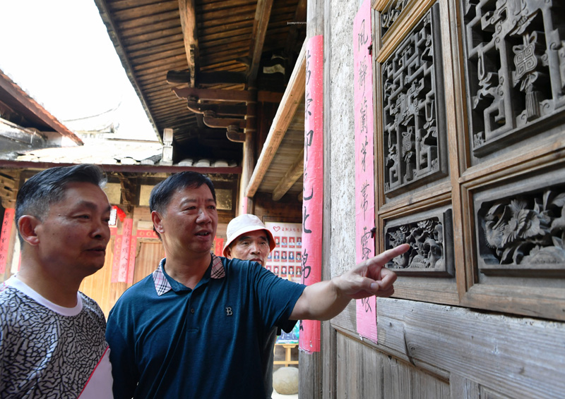 7月19日，游客在永泰县同安镇爱荆庄里听永泰县庄寨民俗专家鲍道文（左二）现场讲解。