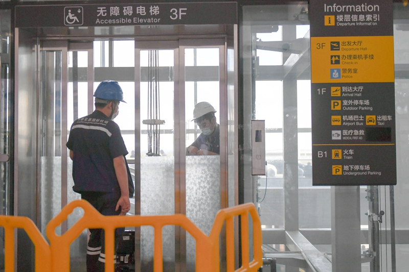 7月20日，工作人员在长春龙嘉国际机场候机楼内安装电梯感应装置按钮。