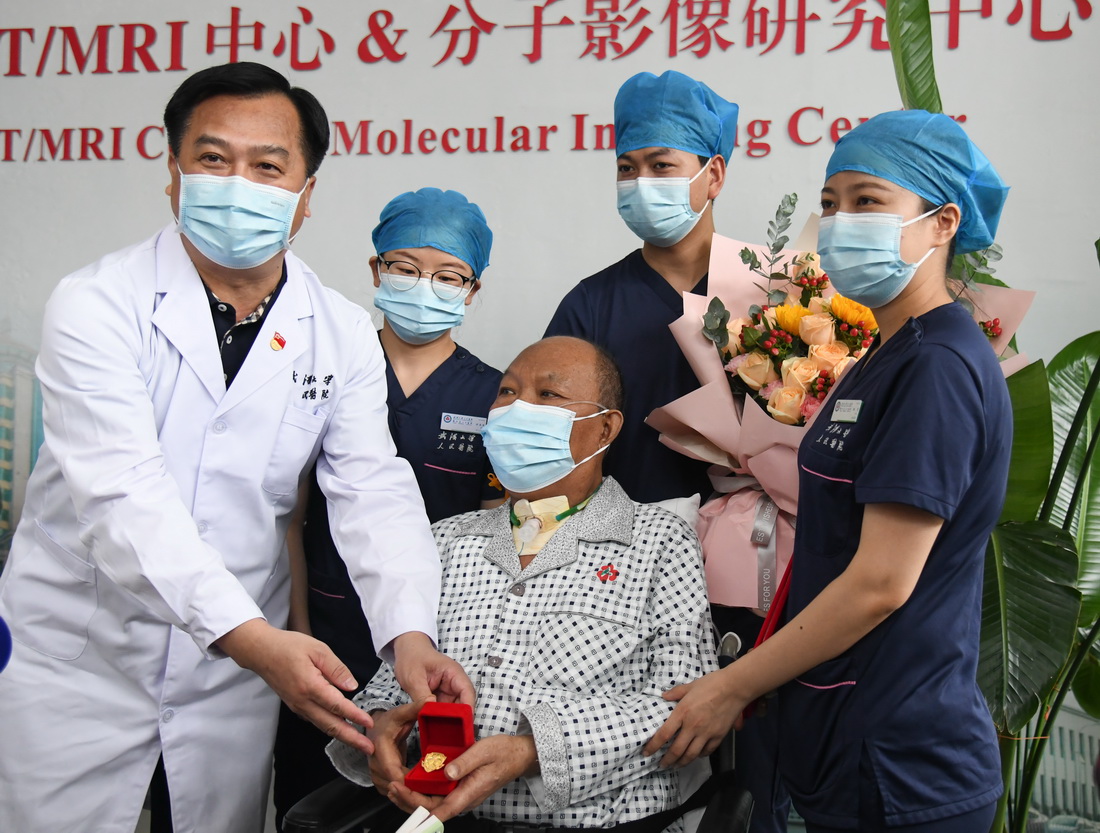 7月21日，武汉大学人民医院党委书记万红慧（左一）为崔先生赠送徽章。