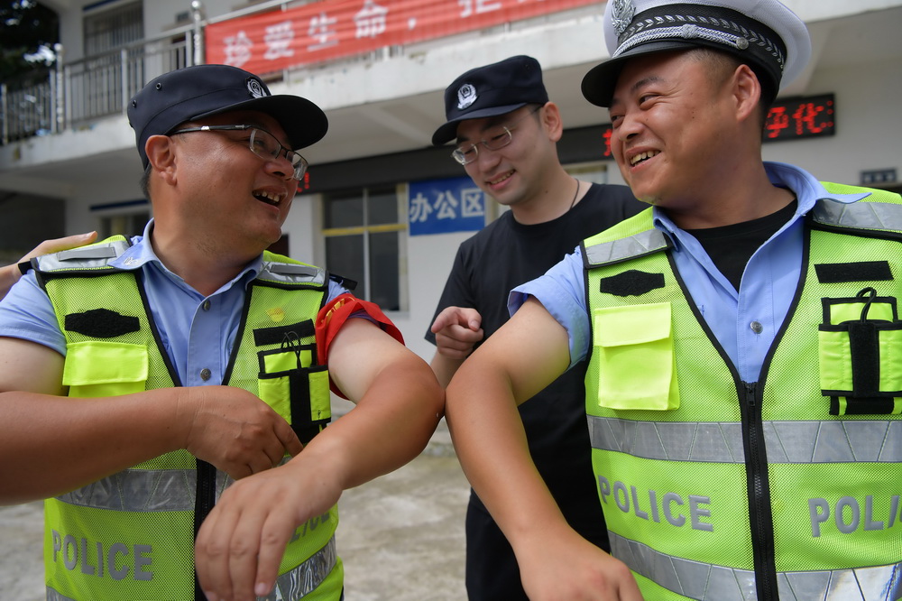 7月22日，梅玉勝（左）和同事在工作間隙開玩笑，查看身上晒黑的程度。