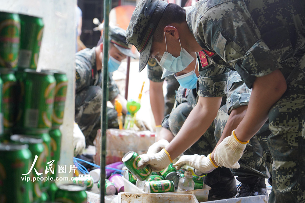 2020年7月25日，武警六安支隊官兵正在幫助受災商戶挑揀、清洗可用的商品。
