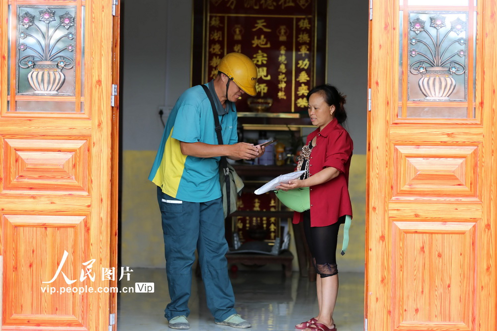 7月28日，在貴州省錦屏縣河口鄉裕和村，張林昌（左）把郵件交到村民的手裡。