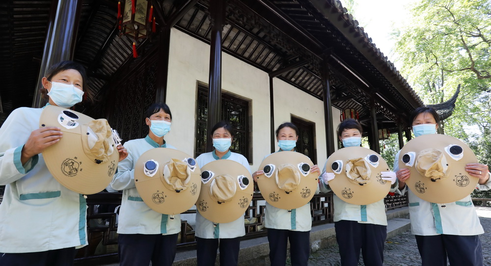 8月12日，江蘇蘇州拙政園的幾名保潔員展示剛領到的太陽能風扇帽。