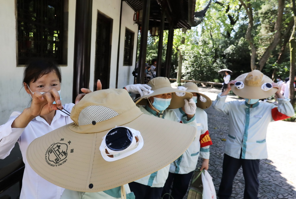 8月12日，江蘇蘇州拙政園的幾名保潔員戴上剛領到的太陽能風扇帽。