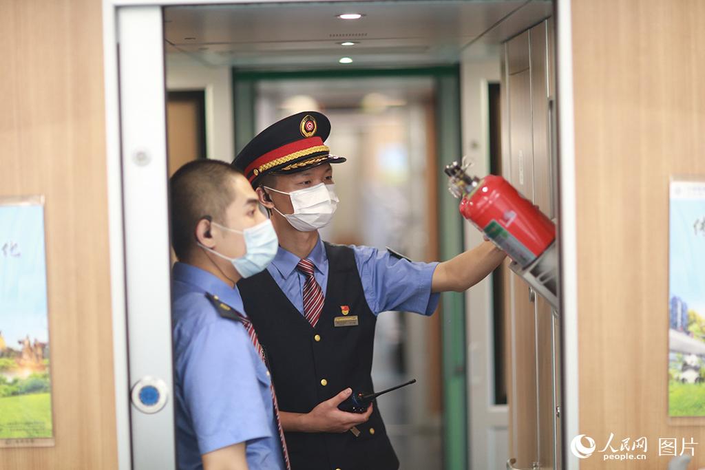 列車長李文航與乘務員在列車始發前對消防設施設備的檢查