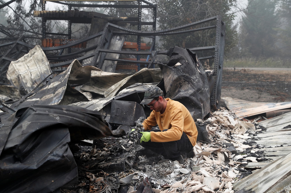 9月13日，在美国俄勒冈州埃斯塔卡达，一名男子查看亲戚家被山火焚毁的物品残骸。新华社/路透