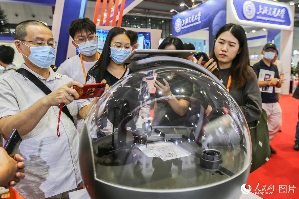 9月15日，观众在第二十二届中国国际工业博览会观看智能画像机器人现场作画。王初/摄