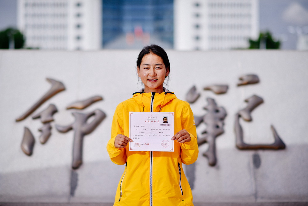 9月21日，在青海省西宁市，拉毛才让在青海师范大学校门外展示自己的大学录取通知书。