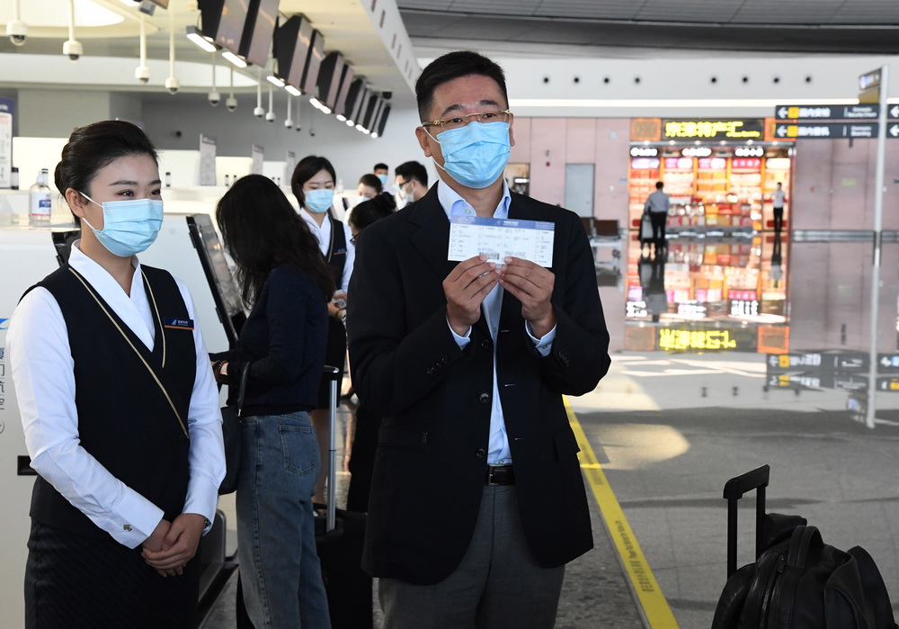 9月22日，在北京大兴国际机场，第1000万名旅客聂先生（前右）展示机票。