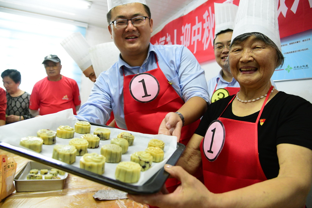 9月24日，在江蘇省鎮江市風車山社區，志願者和社區空巢老人展示共同制作的月餅。新華社發（石玉成 攝）