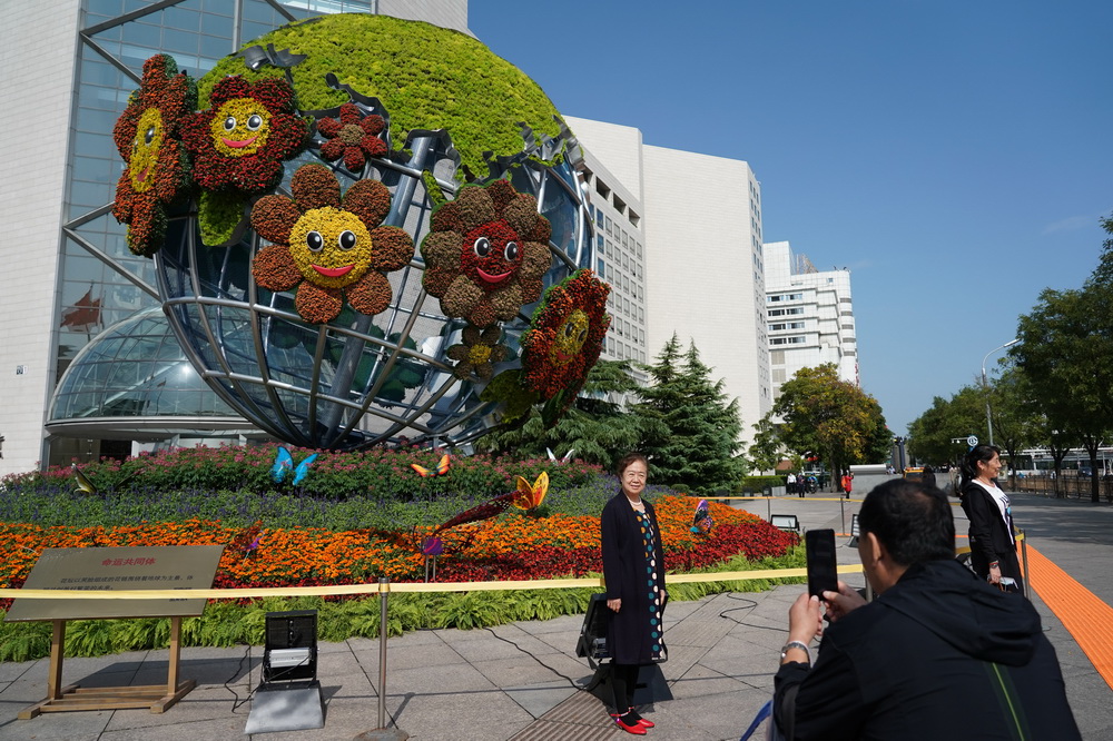 9月30日，游客在西單路口的“命運共同體”花壇前合影。