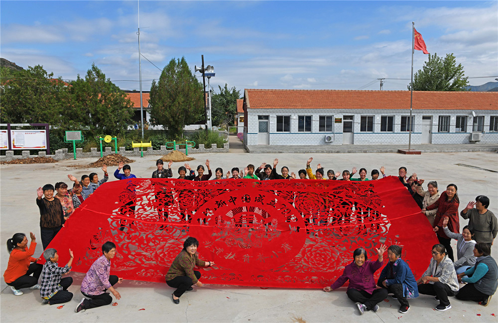 18.河北省承德市豐寧土城鎮毫村溝門村非遺扶貧就業工坊的鄉親們創作巨幅剪紙，慶祝新中國成立70周年。王海琦-攝