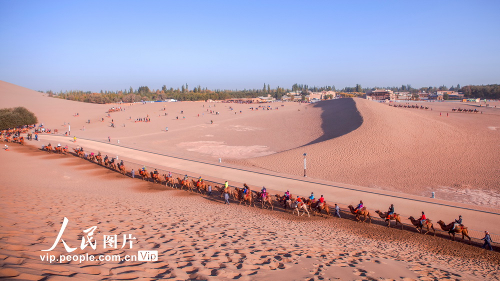 2020年10月7日，在甘肃省酒泉地区敦煌市鸣沙山月牙泉风景区，游客们骑乘骆驼游览大漠风光。