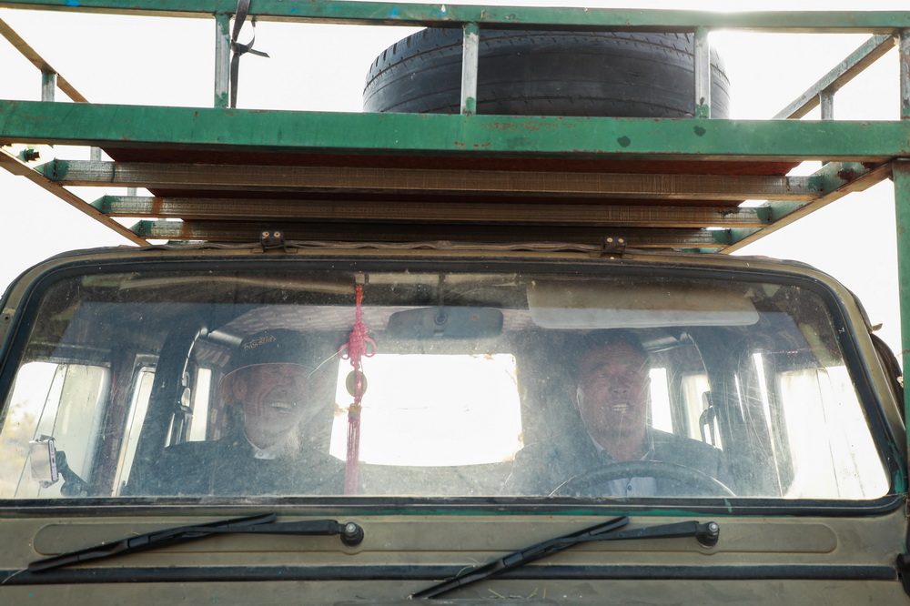 在武威市凉州区长城镇红水村，王天昌（左）乘坐儿子王银吉驾驶的治沙车前往林区浇水（10月23日摄）。