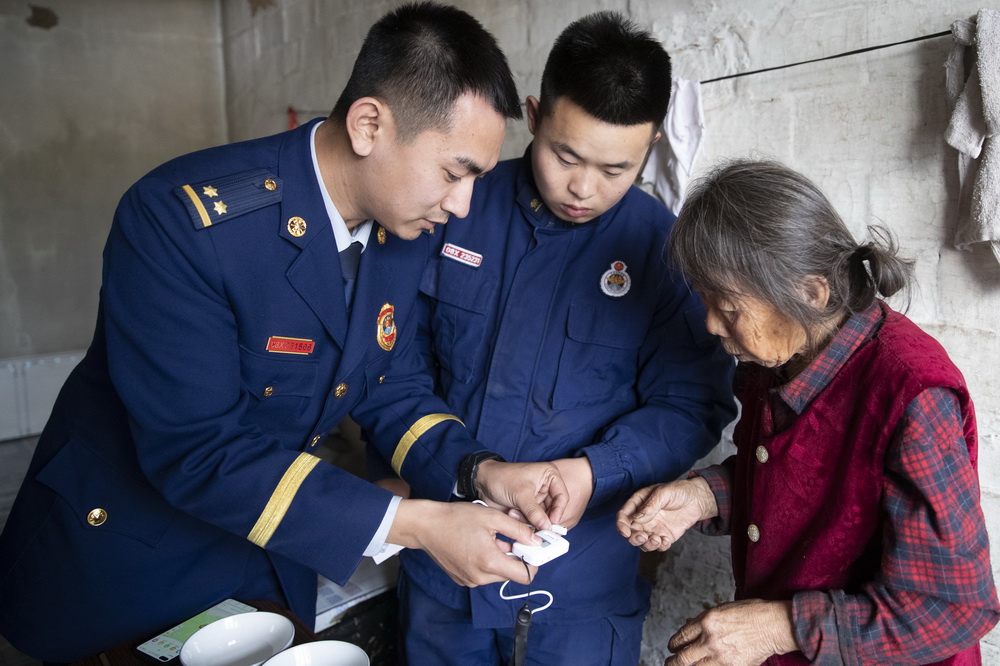 11月6日，北极村消防救援队的李函默（左一）和古誓言（左二）前往村民黄奶奶家送报警器。