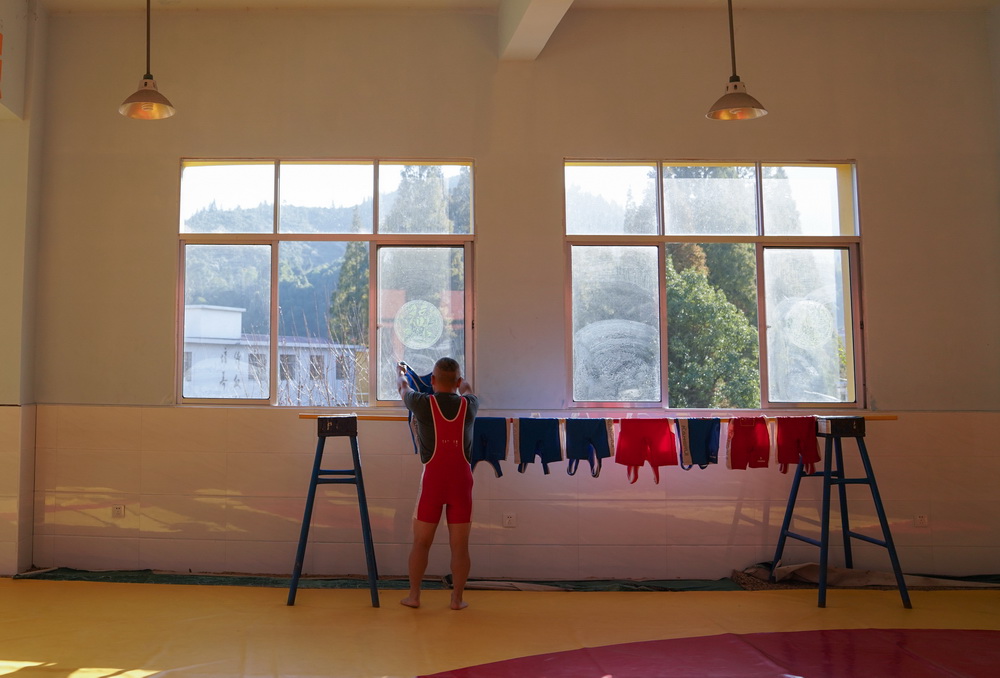 在江西省萍鄉市武功山風景名勝區麻田中心學校的摔跤館，朱志輝在晾晒學生們的摔跤服（11月11日攝）。