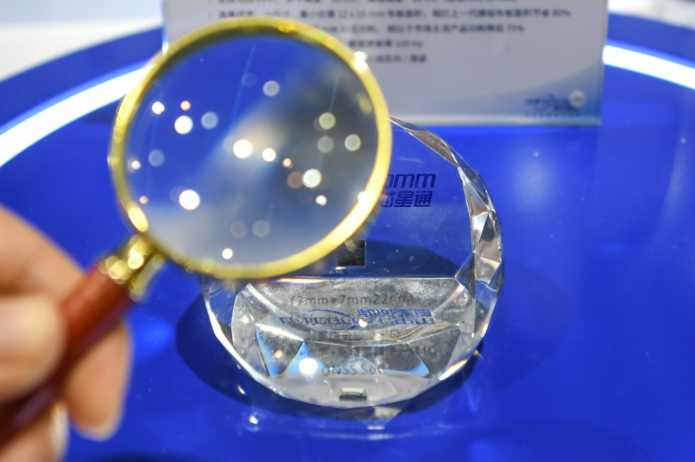 11月24日，觀眾在年會上使用放大鏡查看新一代22nm高精度定位芯片。