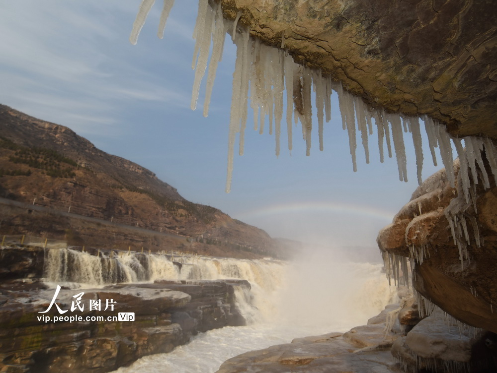 2020年12月4日，游客在山西省临汾市吉县黄河壶口瀑布欣赏冰挂彩虹美景。