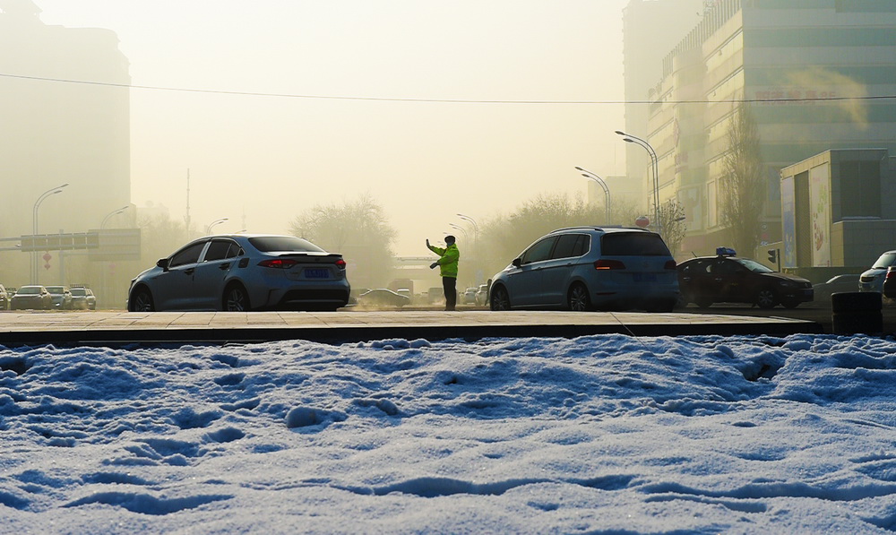 12月16日，在新疆乌鲁木齐，一名交警在路口指挥交通。近日，乌鲁木齐气温骤降，最低温度逼近零下20摄氏度。新华社发（侯昭康 摄）