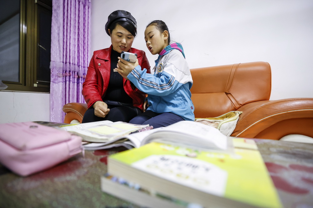 不識字的擺西彥（左）讓上小學的女兒用手機教她認字（11月10日攝）。新華社記者 楊植森 攝
