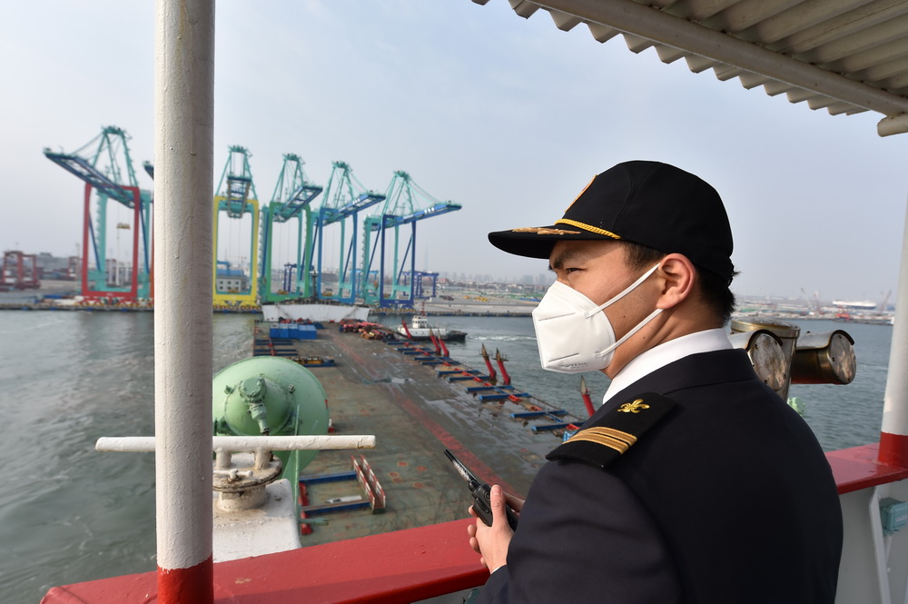 2020年12月28日，天津港引航中心引航員李業在一艘正在離港的船舶上密切關注引航船隻和拖輪的動態。