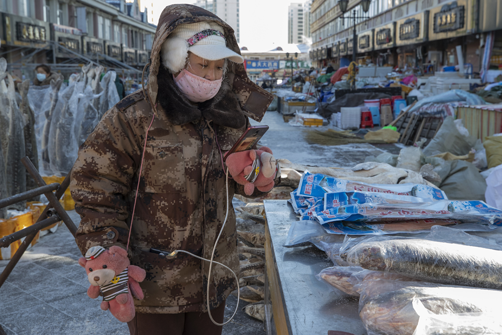 1月9日，商戶在撫遠“東極魚市”內進行直播賣魚。
