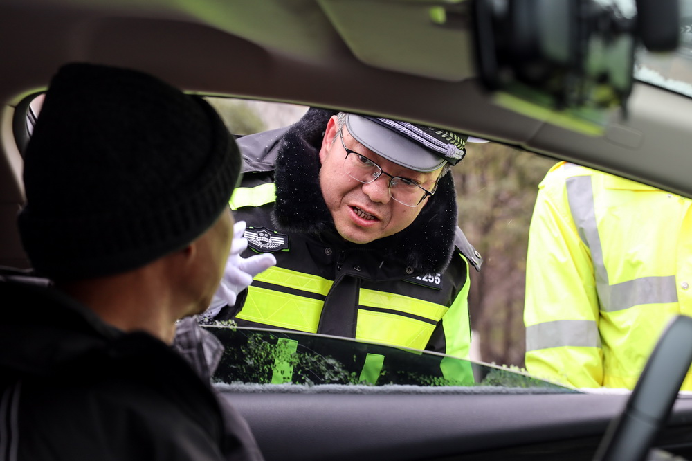 1月11日，交警在盤州市東湖大橋提示司機駕車緩慢通過濕滑路面。