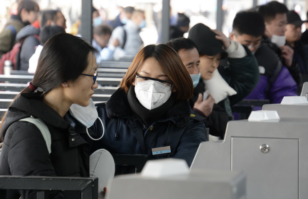 1月12日，北京站工作人員（左二）在檢票口人臉識別系統前進行防疫間隔疏導。