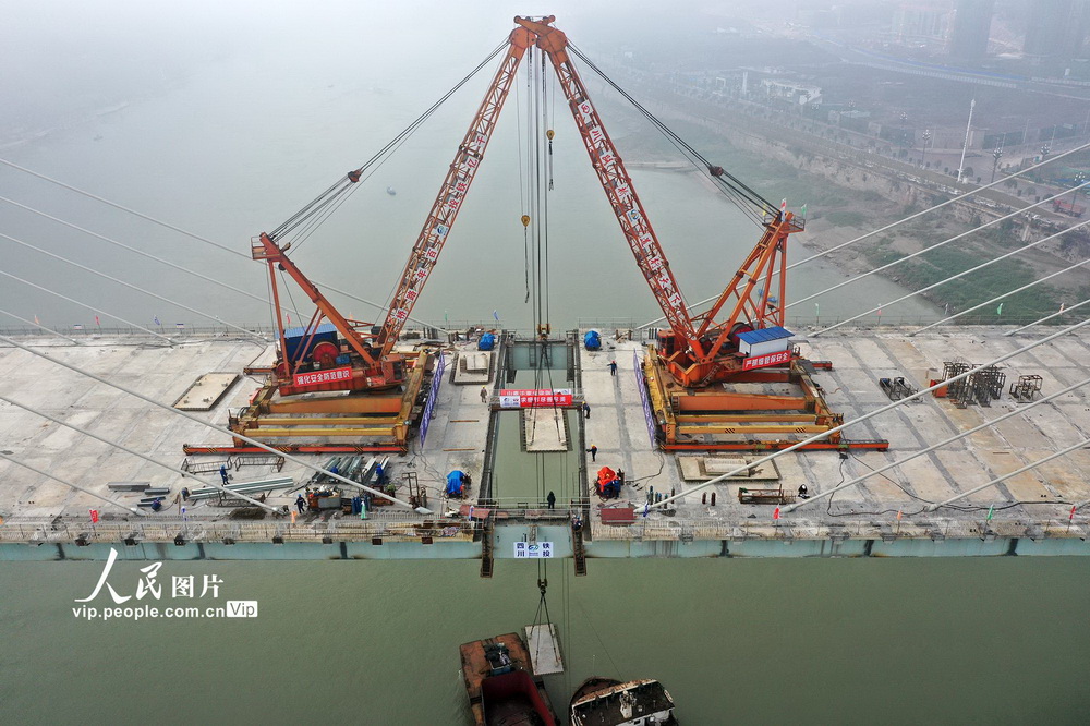 2021年1月12日，在四川省宜賓三江新區鹽坪壩長江大橋建設現場，建設者們正在吊運鋪設最后一根鋼梁的預制板。經過近4天的施工，大橋主橋主跨鋼梁順利合龍。