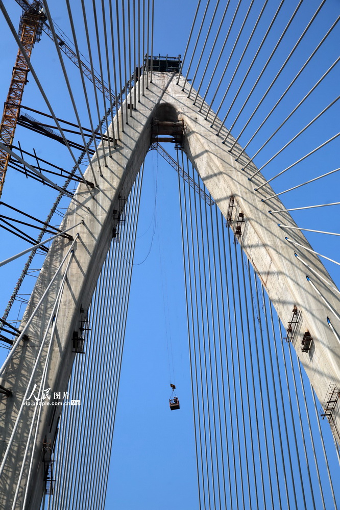 2021年1月12日，在四川省宜賓三江新區鹽坪壩長江大橋建設現場，建設者正乘坐吊廂到索塔頂作業。經過近4天的施工，大橋主橋主跨鋼梁順利合龍。