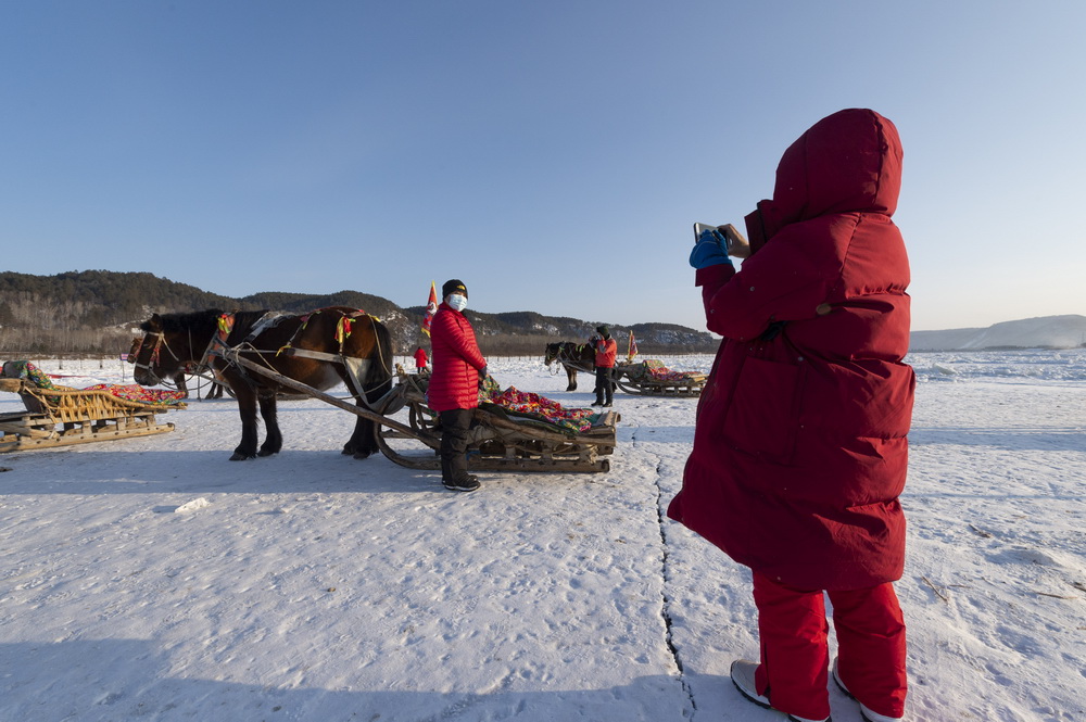 1月13日，遊客在北極村和馬拉爬犁合影。