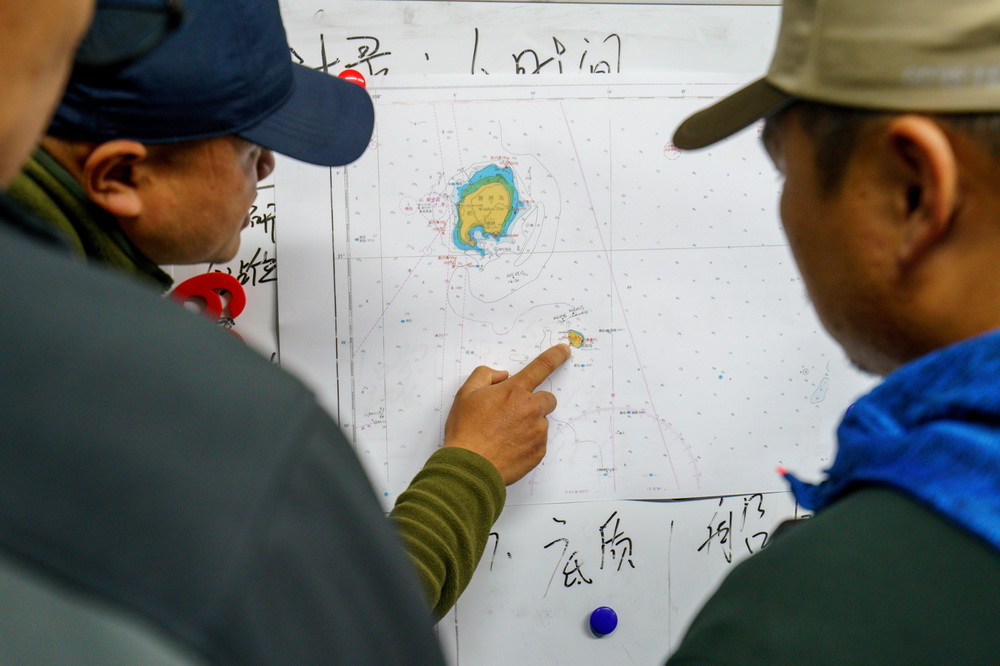 1月13日，徐健（左）在海圖上向陳默指出斜陽島附近布氏鯨可能出現的方位。新華社記者 劉金海 攝