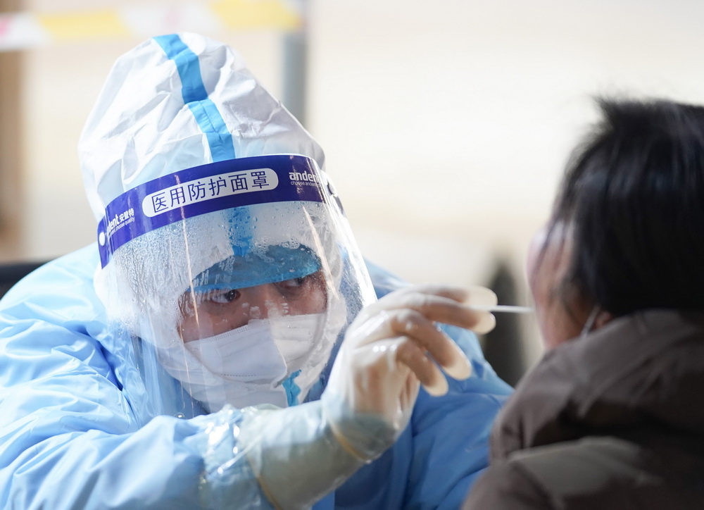 1月20日，在北京市大興區龐各庄鎮一處核酸檢測點，醫護人員為參加核酸檢測的人員進行採樣。新華社記者 鞠煥宗 攝