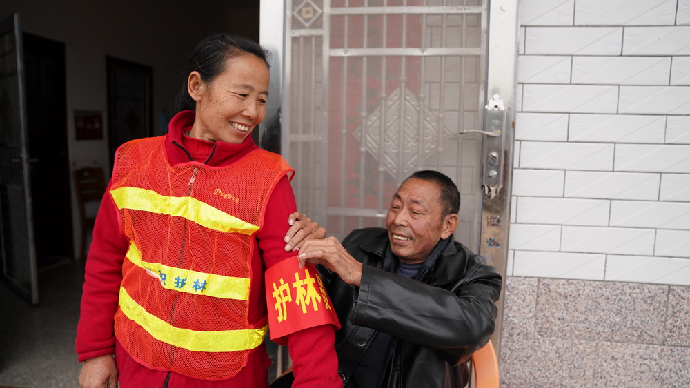 赖际林帮即将外出巡山的妻子刘仁香戴上护林员的袖标（1月22日摄）。