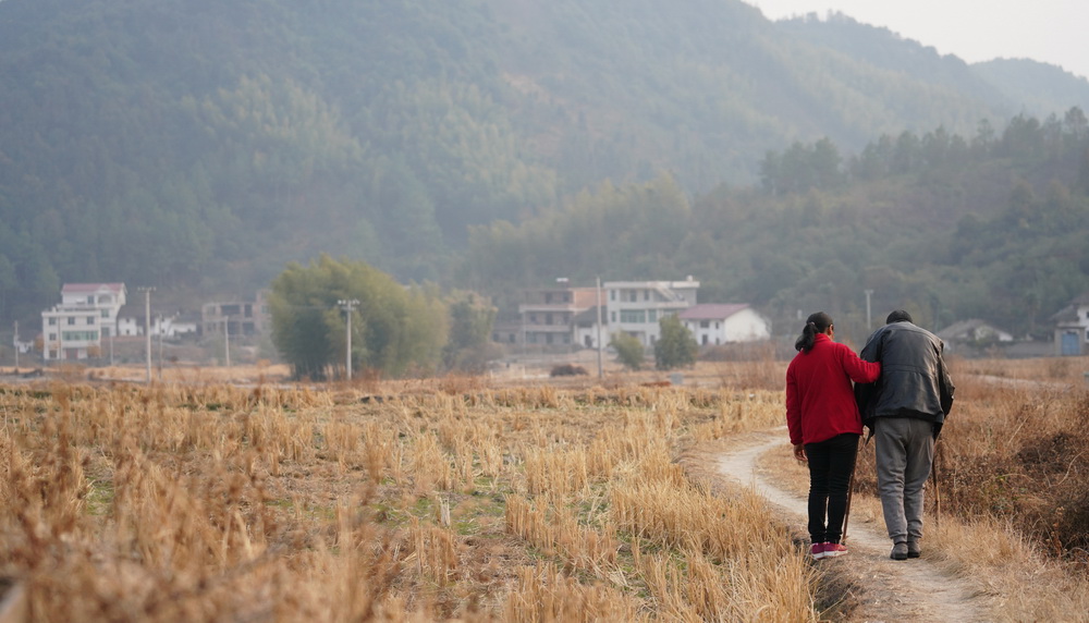 刘仁香搀扶着丈夫赖际林在村里散步（1月22日摄）。