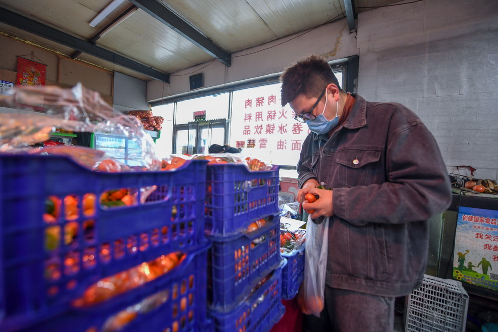 1月25日，王撼東在商店幫助封閉小區內的居民選購水果。新華社記者 顏麟蘊 攝