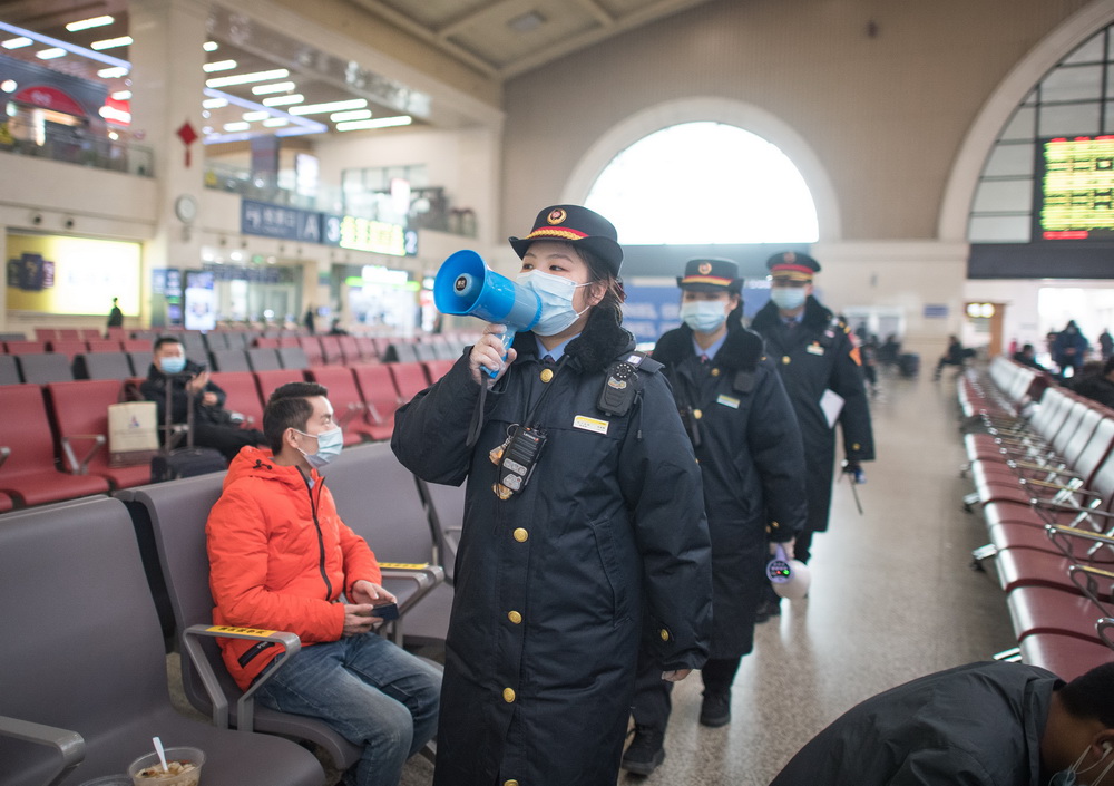 1月28日,汉口火车站的工作人员在候车厅宣讲乘车防疫事项.