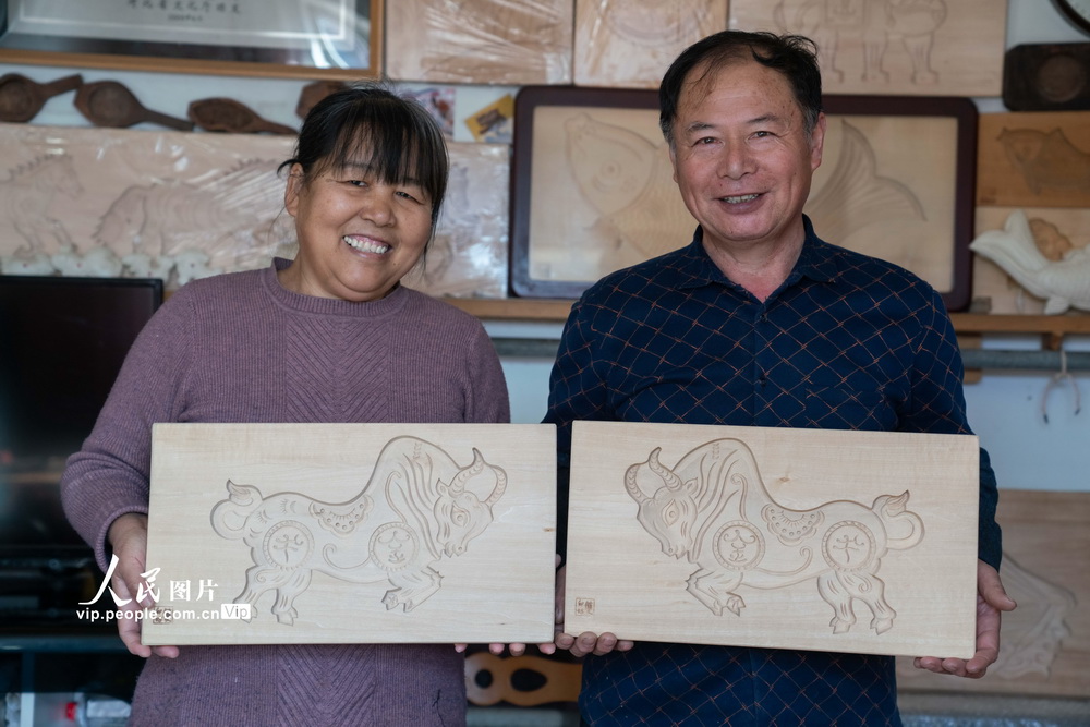 2021年2月2日，河北省黃驊市“面花模子”雕刻非遺傳承人高殿華（右一）和妻子李淑華正在展示雕刻的牛年生肖面花模子。