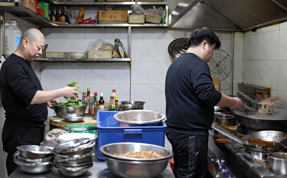 2月2日晚，劉丹的丈夫劉建成（左）在后廚幫助廚師備菜。